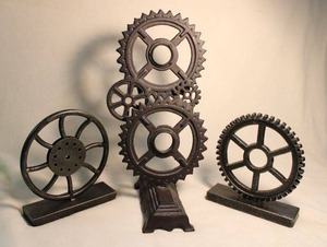 lot 310 image: Figural patinated metal bookends and doorstop in Machine gear form.