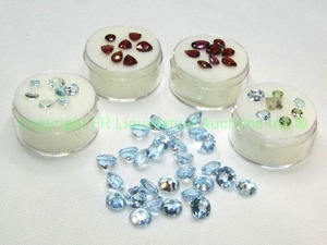 lot 419 image: (5) Garnet White  Mixed Blue gemstones.  One parcel marked 25.00 ctw 7mm Sky Blue Topaz Rounds. Varying sizes and quantities.
