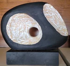 lot 89 image: MID CENTURY ABSTRACT MINIMALIST BLACK & MOTTLED TAN PAINTED WOOD SCULPTURE IN STYLIZED OWL  FACE FORM ON BLACK WOOD BASE 14W x 13H