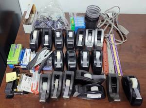 lot 21 image: LARGE LOT OF MIXED OFFICE SUPPLIES INCLUDING STAPLERS, TAPE DISPENSERS, RULERS, STAPLES, TAPE, AND MORE AS SHOWN.
