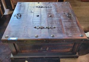lot 90 image: SQUARED WOODEN WITH METAL HARDWARE ACCENT TABLE IN STYLE, COLOR, AND CONDITION SHOWN. 2-HINGED SECTIONS ON TOP OPEN FOR STORAGE AREA. APPROX 39 12 x 39 12 x 17 12 H.