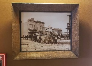 lot 213 image: Laton Anton Huffman Framed Print, Bull Train At Main and Park Streets, Miles City Montana 1881  - 18 x 15