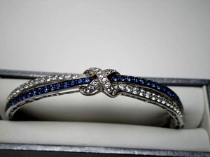 lot 1 image: Sterling silver blue &amp white diamond hinged bracelet in classic traditional crossover form. Marked 925 CO. Approx. 34 cttw (approx. 84 points). Diamonds tested. Has a safety catch, in a fitted Bachendorfs jewelry box.&nbsp