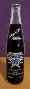lot 82 image: 1984 DALLAS COWBOYS SILVER SEASON COMMEMORATIVE 10 OUNCE COCA-COLA BOTTLE 1960-1984 AS SHOWN. CELEBRATING 25 YEARS IN THE NFL. CHECK IT OUT