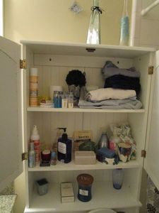 lot 29 image: CONTENTS OF BATHROOM, CHANEL No. 5 PERFUME, CANDLES, LOTION, CONTAINERS, TOWELS, SOAPS, GLASS JARS W COLORED SAND, CLEANING PRODUCTS, SOAP DISPENSER, PICS ON WALL. CABINET NOT INCLUDED