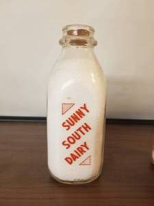 lot 57 image: Sunny South Dairy quart glass milk bottle with lid