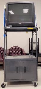 lot 23 image: (1) ROLLING AV CART AND (1) SHARP TV MODEL 27H-S60 WITH REMOTE AS SHOWN. CART APPROX. 30.25 W x 20 D x 54 H.