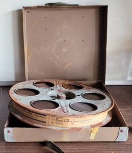 lot 101 image: VINTAGE METAL MOVIE REEL WITH FILM STRIP AND SHIPPING CASE AS SHOWN.
