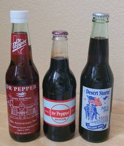 lot 69 image: (1) 1991 DESERT STORM WELCOME HOME, (1) 2002 FIFTH ANNIV. LONE STAR PARK, AND (1) DR. PEPPER MUSEUM COMMEMORATIVE UNOPENED BOTTLES AS SHOWN. (SOLD 3 X THE MONEY)