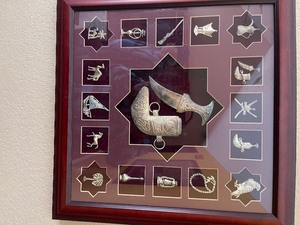 lot 11 image: Framed in shadow box - Silver pieces camels, horses, palm trees knifes, boots, tea pots and more  from OMAN