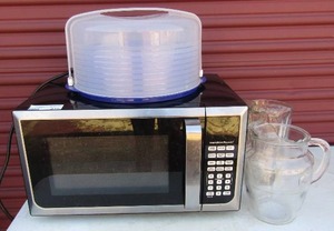 lot 216 image: Hamilton Beach black working microwave, 2 glass water pitchers covered plastic cake plate