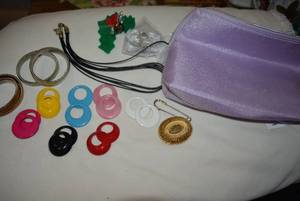 lot 342 image: Lancme pink zippered cosmetic case with jewelry. Includes a large filigree brooch pin, leather cord necklace, stretch sleeve fasteners, large safety pin brooch plus