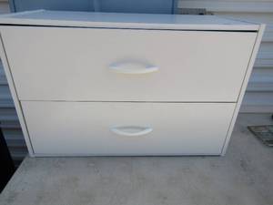 lot 33 image: White 2 drawer storage full of office supplies ( staples, envelopes, pens pencils etc.)