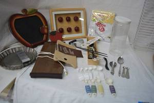 lot 69 image: Misc. Kitchen Lot Several Measuring Spoon Sets, Electric Hot Plate, Oblong Vinyl Tablecloth Still in Packaging, Apple Shaped Chalkboard and Shadowbox