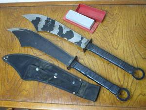 lot 4 image: 2 LARGE CHINESE SWORD-MACHETES (DADAO), TOTAL LENGTH 29.75, BLADE LENGTH 17.75, BLADE WIDTH AT LARGEST POINT 4.25, 1 HAS SHEATH, LARGE SHARPENING STONE INCL.