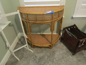 lot 38 image: RATTAN DEMILUNE TABLE 29 BY 32,  ROLLING MAGAZINE RACK 14 BY 12 BY 10 (DAMAGE TO FINIAL)