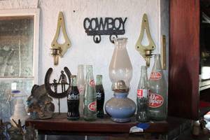 lot 28 image: Contents of Shelf and wall vintage bottles, Brass candle holders, and cowboy key rack