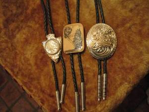 lot 7 image: 3 BOLO TIES, SILVER ARROWHEAD HAS 1937 BUFFALO NICKLE W OBVERSE SIDE SHOWING, SCRIMSHAW W BOAT BLOWN BY WIND, SILVER WESTERN DESIGN