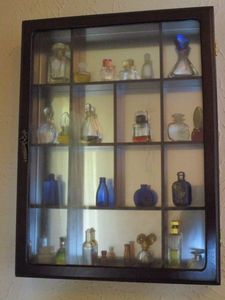 lot 113 image: WALL MOUNTED DISPLAY SHELF W DOOR CONTAINING MANY VINTAGE PERFUME BOTTLES