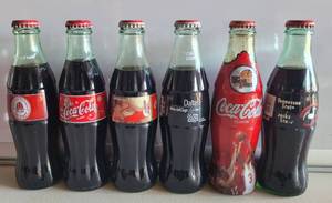 lot 136 image: LOT OF 6 COMMEMORATIVE COCA-COLA BOTTLES AS SHOWN.