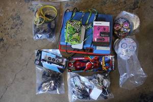 lot 155 image: Misc. Lot Tins, Earbuds, Spider-man Toy, Various Chargers, Sunglasses, Vintage Phonograph as shown
