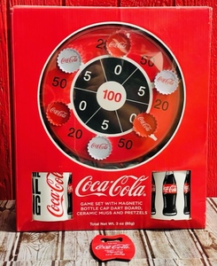 lot 126 image: Coca-Cola Game Set With Magnetic Bottle Cap Dart Board, Ceramic Mugs, and Pretzels WBottle Opener