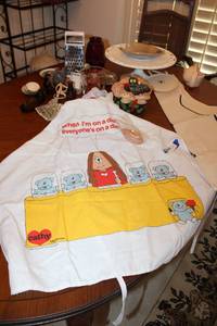 lot 112 image: Misc. Lot Pyrex Measuring Cup, Grater, Pedestal Cake Plate, UV Sunglasses,  Apron and More