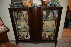 lot 29 image: Antique 2 Door Curio with Curved Wooden Center Panel and Glass Shelves - Contents Sold Separately - Has Skeleton Key, 4Ft. W x 15D x 4 Ft. H (PICKUP AFTER 3Pm Saturday or Sunday)