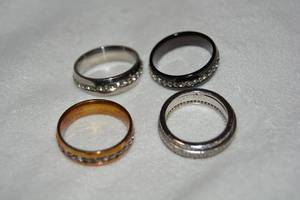 lot 631 image: (4) Polished stainless steel band rings. One is a spinner ring. All marked 316L S. Steel. (30-9, Spinner ring is 8)