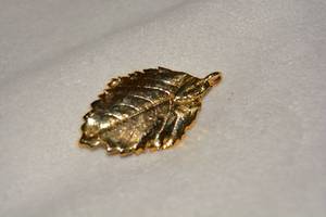 lot 656 image: 22-24K hand dipped Hawaiian Maile leaf (Alyxia oliviformis) pendant. Natural Maile leaves are used in Hawaiian leis. A symbol of unity, respect, peace, friendship and love with origins in oild Hawaii.