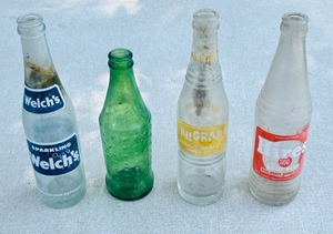 lot 142 image: Four Vintage Glass Soda Bottles- Hires Root Beer, Nu Grape, Sprite, &amp Welchs