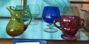 lot 137 image: Yellow bubble galss pitcher  4    DBL handled red   4 glass cup,    5 colored glass wine glasses