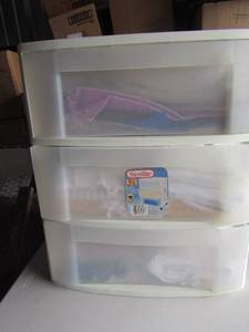 lot 107 image: 3 drawer white portable shelfing unit, full of wash towels , table cloths, placemats