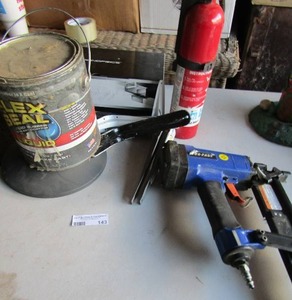 lot 143 image: small fire extinguisher, can of used flex seal, blue and black nail gun, various brakets and 1 large pot.