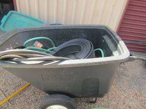 lot 193 image: Black 2 wheel yard wagon, needs air. Comes with flower garden edging black new roll, 2 used water hoses