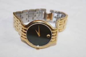 lot 67 image: Movado watch. Model MB 17 136 1303  14160431 Swiss made. Textured polished gold flex band and sleek black face.