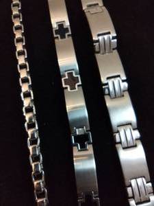 lot 104 image: (3) Stainless steel unisex bracelets. 9 and 2-8.5L Enamel on one cross station link is damaged.