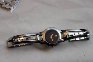 lot 393 image: Movado diamond non working watch. Silver w gold accents. Diamonds tested. 18 diamonds. Model 81 E4 1842 Also includes some Movado links for watches.