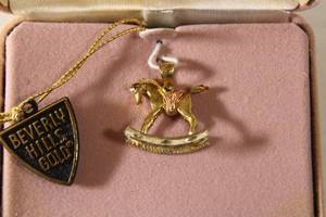 lot 168 image: Jewelry 14K yellow gold signed Beverly Hills Gold laser cut rocking horse pendant. Marked 14K Beverly Hills Gold in box with booklet.