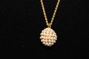 lot 408 image: Signed Joan Rivers faux seed pearl decorated round pendant on a separate 28L gold tone chain. Has jewelry hang tag.