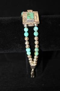 lot 475 image: Sterling Silver Southwest Traditions branded (authentic Kingman) Turquoise double strand bracelet with decorated center panel. Marked Sterling. 7.5L w information sheet, logo branded pouch and box.