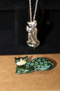 lot 476 image: Sterling Silver feline jewelry. Includes a 20 sterling chain with removable cat pinpendant. (Both marked sterling) and an enameled resting cat pin (marked Silver).