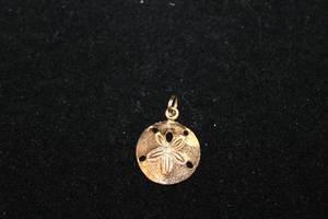 lot 443 image: 14K yellow gold Plumb charm in sand dollar form. Marked JTM 14K P.