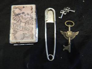 lot 183 image: 2 small decorative keys, one decorative watch face keys, one xxl safety pin and live free skull cigarette case