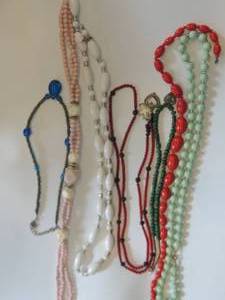 lot 74 image: Several glass, wood, and stone necklaces in pink, white blue  red and more.