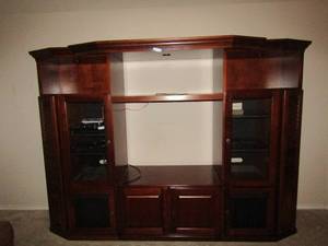 lot 100 image: 5 piece  Livingroom entertainment center, 2 side movie storage pull outs, 3 top space book or nick knack area, 2 side glass doors, 4 bottom door storage area, has lights works great
