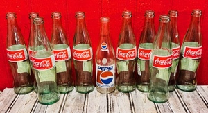 lot 269 image: Ten Vintage Green Tinted Coca-Cola Bottles and One Pepsi From Mexico - In Spanish