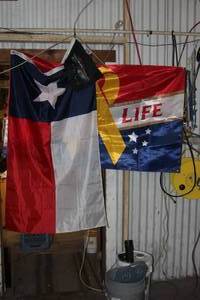 lot 52 image: High Life yellow ribbon flag, Texas Flag, and Harley Davidson Auto Flag