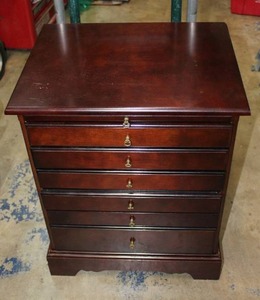lot 141 image: Cherry finish jewelry stand with 6 felt lined and compartmented drawers. Pull out tray at top. Specific areas for rings, necklaces, earrings etc. Brass finish handles. 19.5W x 26H x 15D Very slight scratches to top
