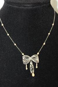 lot 185 image: 10K White Gold vintage filigree pearl station necklace in bow form. Marked 10K. 14L